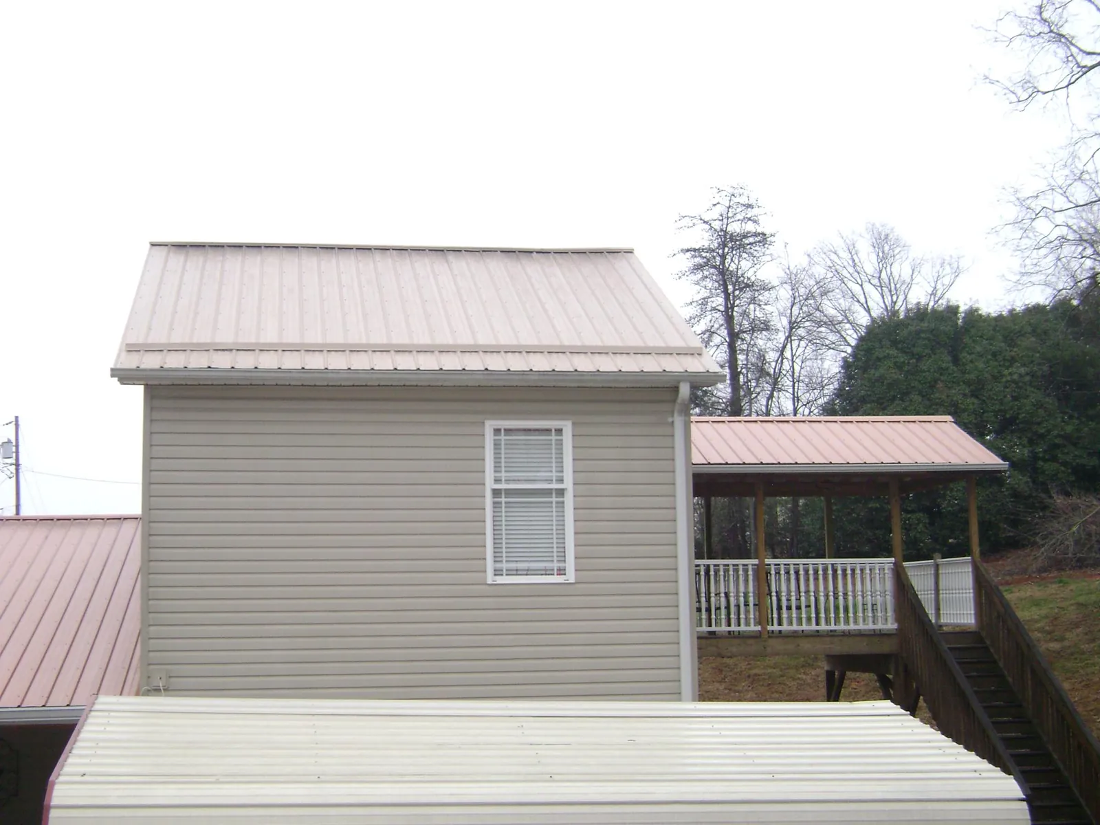 Tan metal roofs on a two story addition and attached porch, from a Roof Replacement job in Blaine